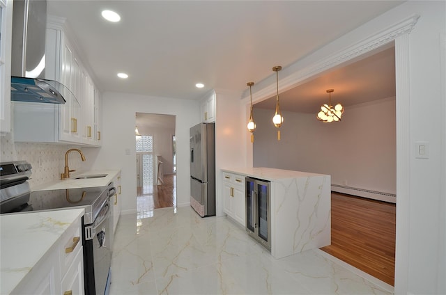 kitchen featuring a baseboard heating unit, appliances with stainless steel finishes, wall chimney range hood, white cabinets, and sink