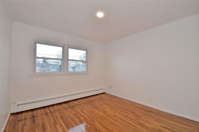 empty room featuring a baseboard heating unit and light hardwood / wood-style floors