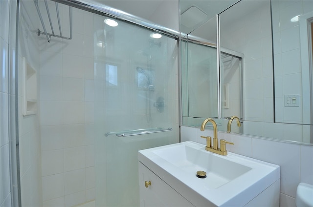 bathroom featuring tile walls, toilet, a shower with door, and vanity