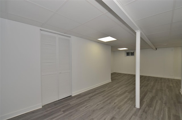 basement featuring dark wood-type flooring and a paneled ceiling