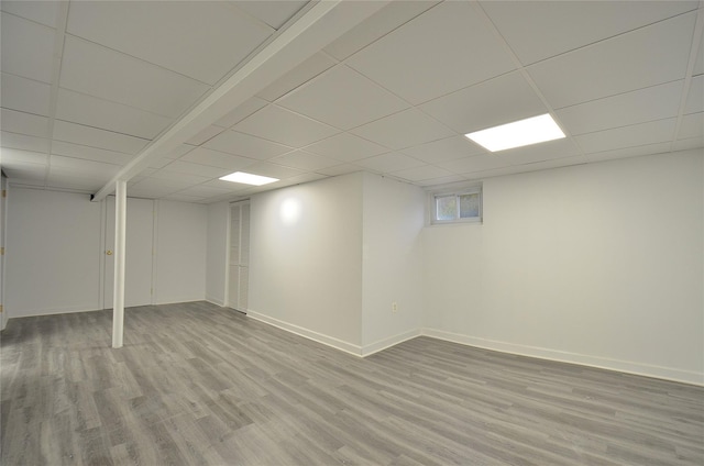 basement featuring a drop ceiling and light hardwood / wood-style flooring