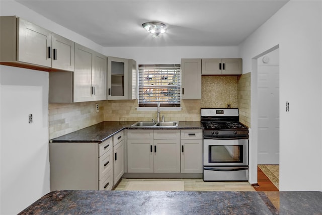 kitchen with sink, backsplash, gray cabinets, and stainless steel gas range oven