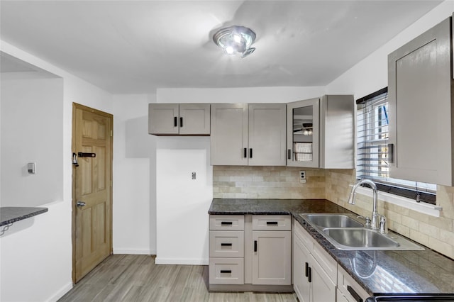 kitchen with sink, backsplash, light hardwood / wood-style flooring, and gray cabinetry