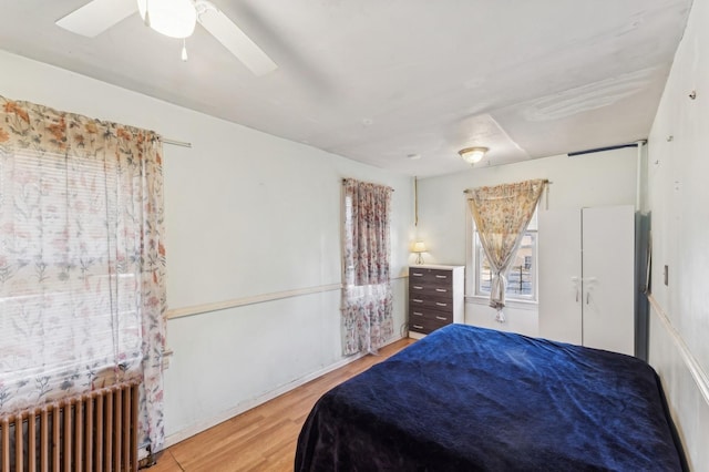 bedroom featuring ceiling fan, radiator heating unit, and wood-type flooring