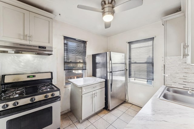 kitchen featuring appliances with stainless steel finishes, tasteful backsplash, sink, light tile patterned floors, and ceiling fan