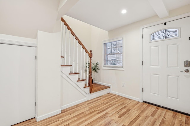 entrance foyer featuring beamed ceiling, a healthy amount of sunlight, and light hardwood / wood-style flooring