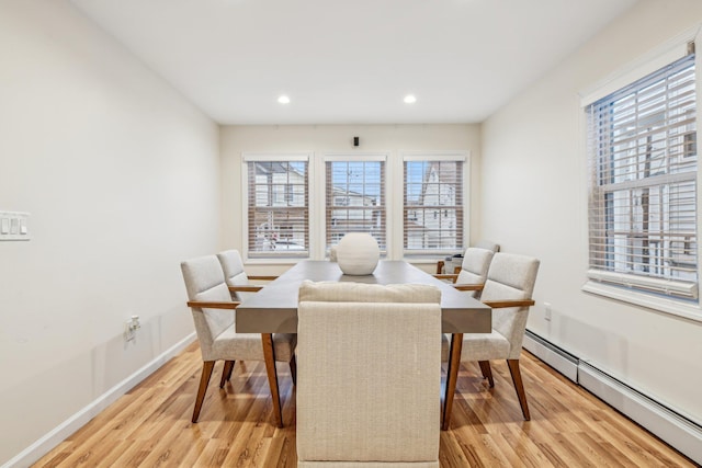 dining space with a baseboard heating unit and light wood-type flooring