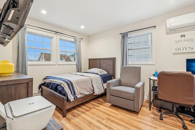 bedroom featuring a wall mounted AC and light hardwood / wood-style floors