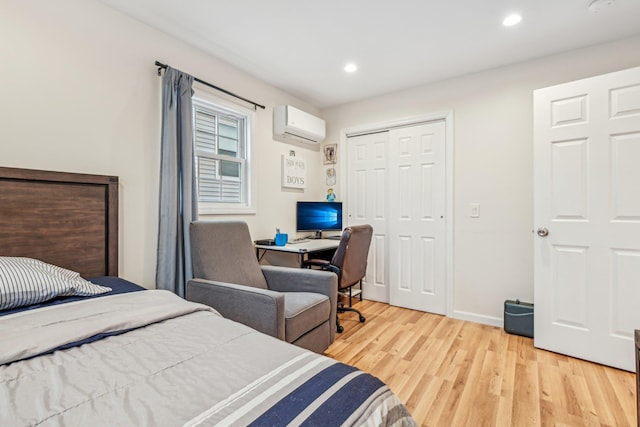 bedroom featuring a closet, a wall unit AC, and light hardwood / wood-style flooring