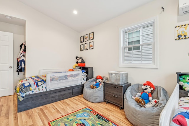 bedroom featuring a wall mounted AC and light hardwood / wood-style floors