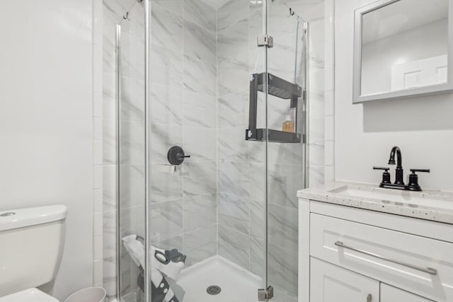 bathroom with vanity, a shower with door, and toilet