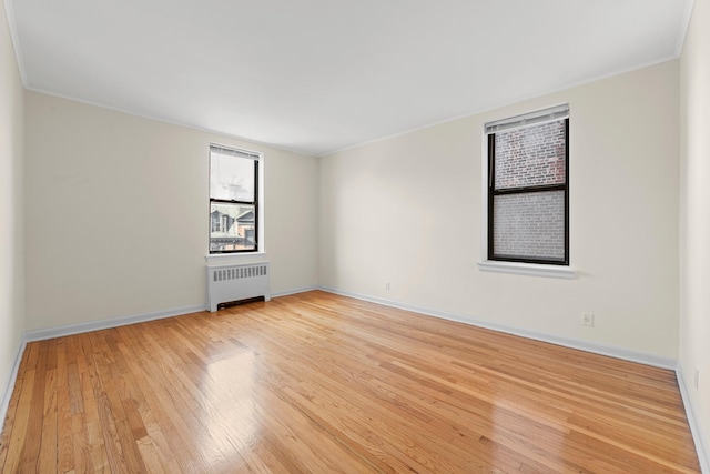 empty room with radiator heating unit and light hardwood / wood-style flooring