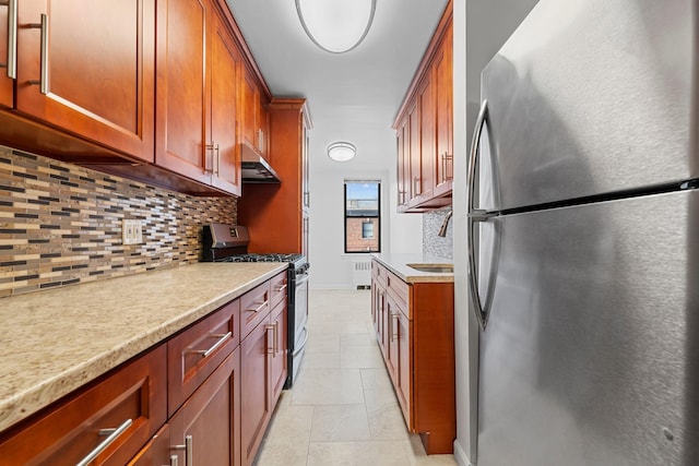 kitchen with decorative backsplash, appliances with stainless steel finishes, radiator, sink, and light tile patterned floors