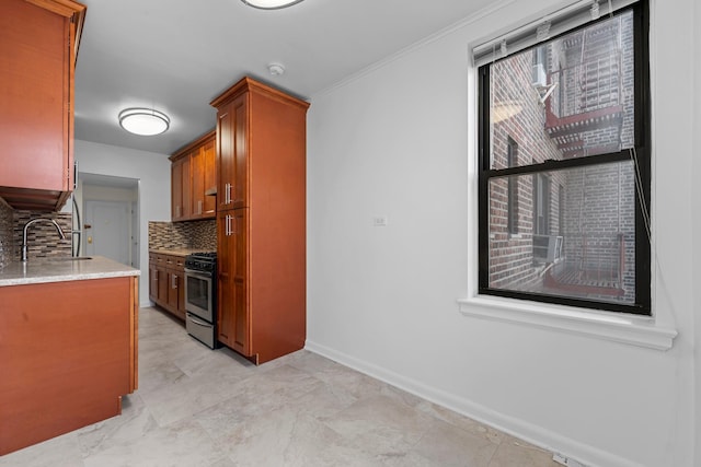 kitchen featuring backsplash, stainless steel range with gas cooktop, sink, and light stone counters