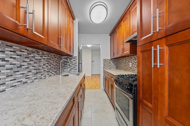 kitchen with decorative backsplash, sink, light stone countertops, and stainless steel range with gas stovetop