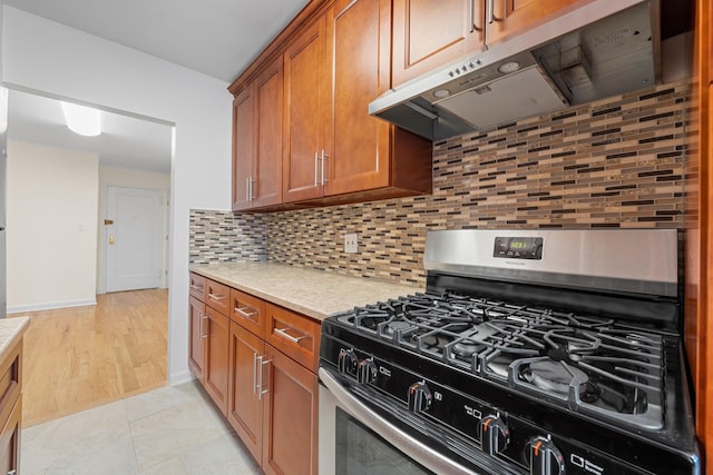 kitchen featuring light stone countertops, stainless steel range with gas cooktop, backsplash, and light tile patterned floors