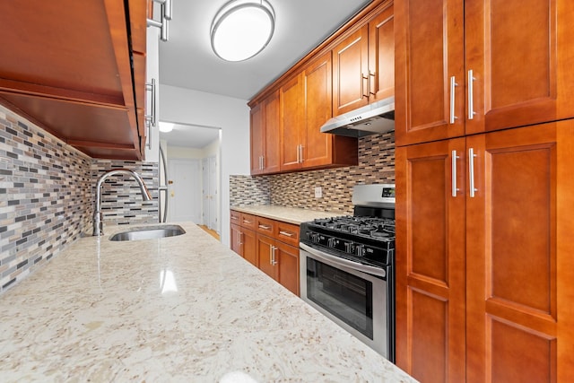 kitchen featuring decorative backsplash, light stone counters, sink, and stainless steel gas range