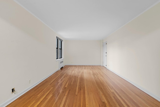 empty room featuring light hardwood / wood-style flooring, radiator, and ornamental molding