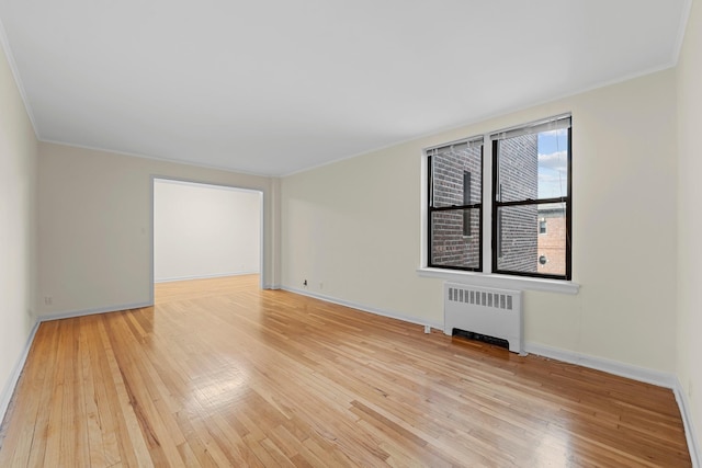 spare room featuring hardwood / wood-style flooring, crown molding, and radiator