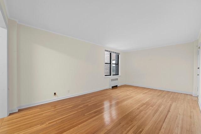 unfurnished room featuring radiator heating unit, light hardwood / wood-style flooring, and crown molding