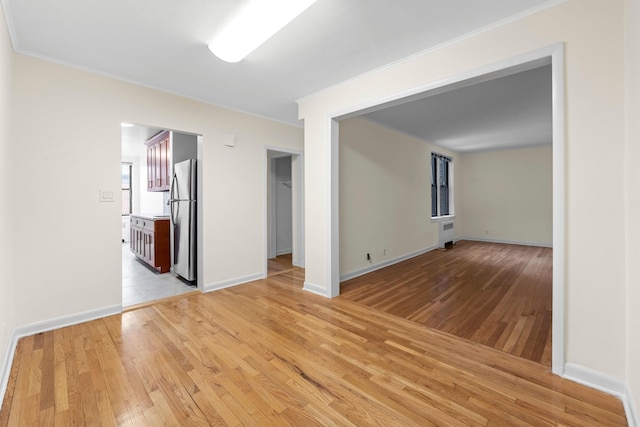 unfurnished room featuring light hardwood / wood-style floors, ornamental molding, and radiator