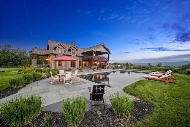 back of property with a balcony, a yard, and a patio area