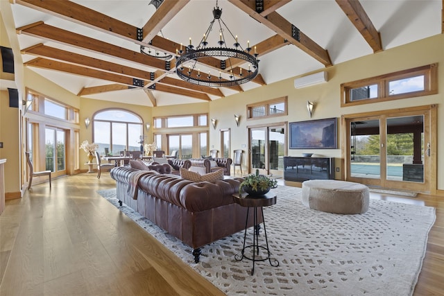 living room featuring a chandelier, high vaulted ceiling, light hardwood / wood-style flooring, and an AC wall unit
