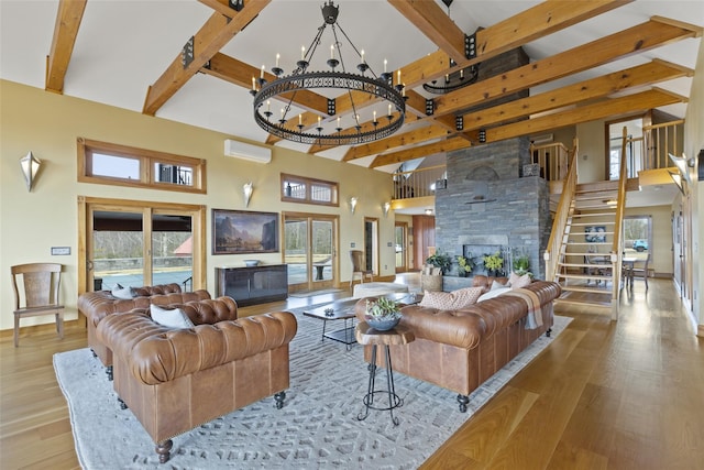 living room with a wall mounted AC, a notable chandelier, a fireplace, and light hardwood / wood-style floors