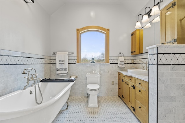 bathroom featuring a tub to relax in, lofted ceiling, toilet, and vanity