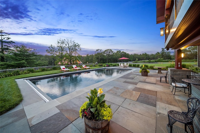 pool at dusk featuring a patio area