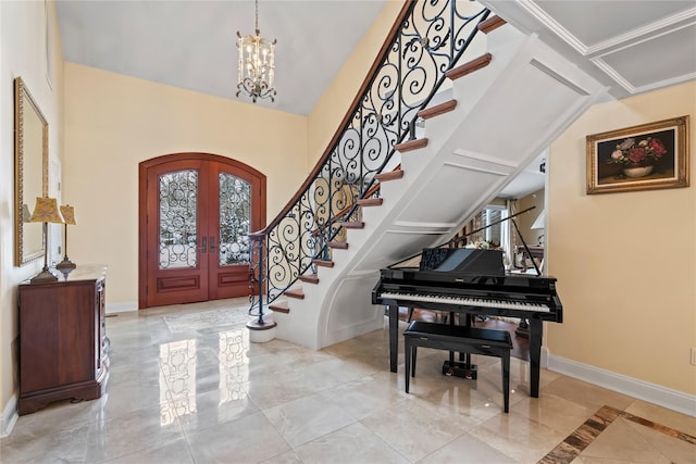 foyer entrance with crown molding, french doors, and an inviting chandelier