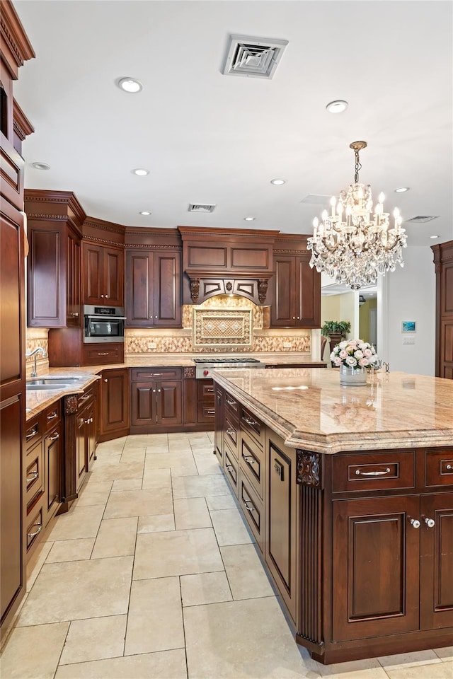 kitchen with decorative backsplash, decorative light fixtures, sink, and a kitchen island