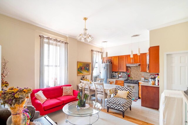 living room with water heater, crown molding, light hardwood / wood-style flooring, and a notable chandelier