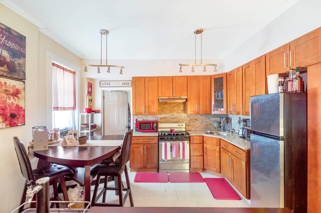 kitchen with gas stove, sink, hanging light fixtures, and stainless steel refrigerator