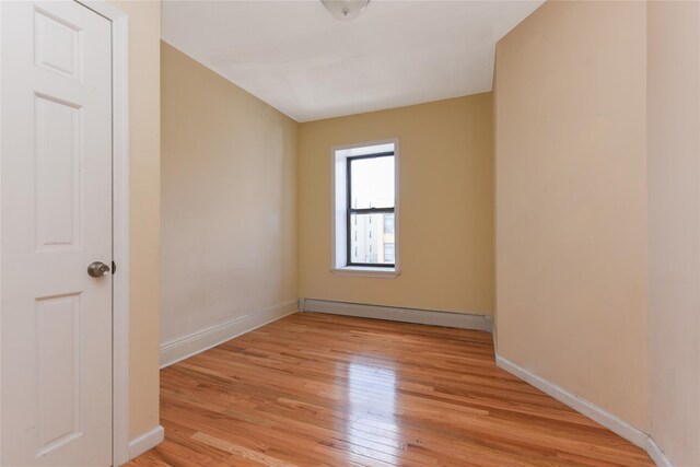 unfurnished room with a baseboard radiator and light hardwood / wood-style flooring