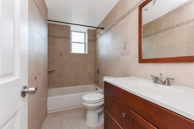 full bathroom with tiled shower / bath combo, tile patterned flooring, toilet, vanity, and tile walls