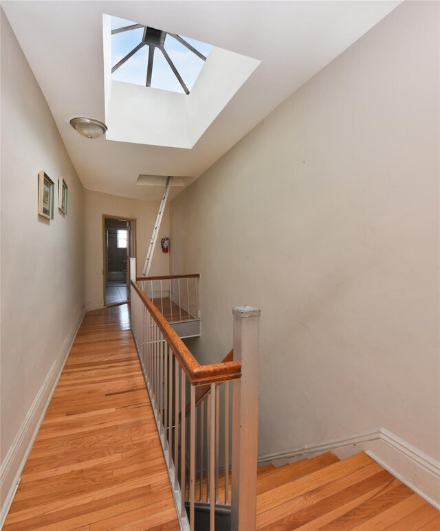 stairway with a skylight and hardwood / wood-style floors