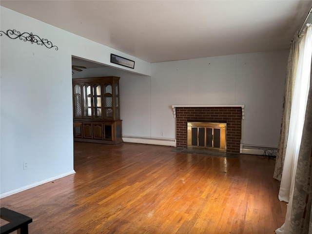 unfurnished living room featuring dark hardwood / wood-style flooring, a fireplace, and a baseboard heating unit