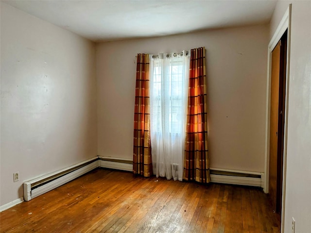 spare room with hardwood / wood-style floors and a baseboard heating unit