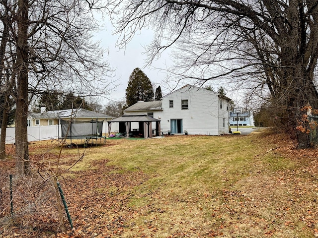 rear view of property featuring a lawn and a trampoline