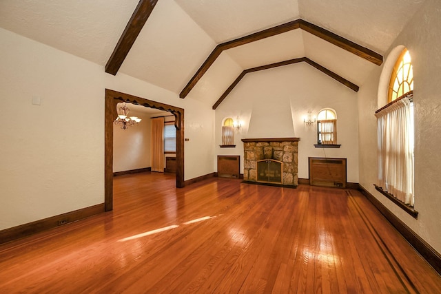 unfurnished living room with a fireplace, hardwood / wood-style flooring, an inviting chandelier, and lofted ceiling