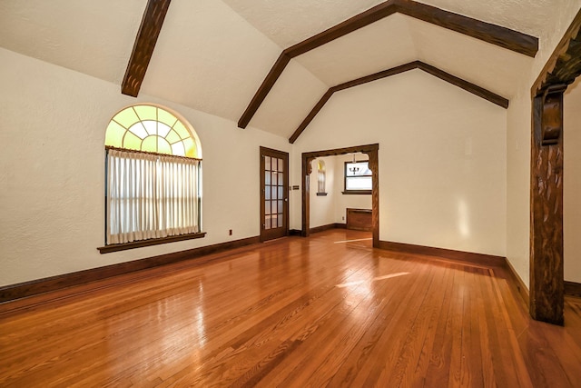 unfurnished living room featuring lofted ceiling with beams and wood-type flooring