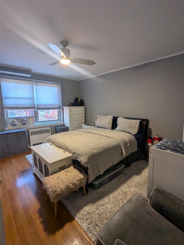 bedroom featuring crown molding, hardwood / wood-style flooring, radiator heating unit, and ceiling fan