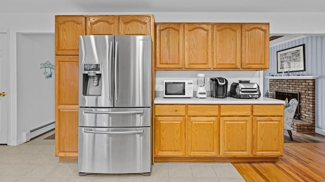 kitchen with a fireplace, stainless steel refrigerator with ice dispenser, and a baseboard heating unit