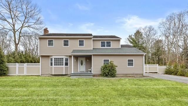 view of front of house with a front lawn, a chimney, and fence