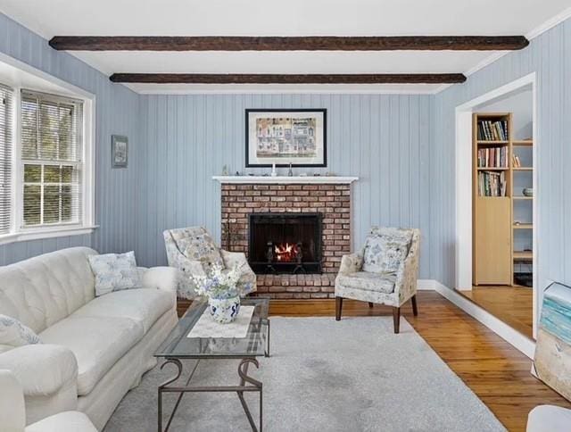 living area with a brick fireplace, wood finished floors, and beam ceiling