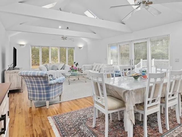 dining room featuring lofted ceiling with beams, light wood-type flooring, and a ceiling fan