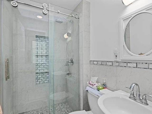 bathroom featuring a stall shower, a sink, and toilet