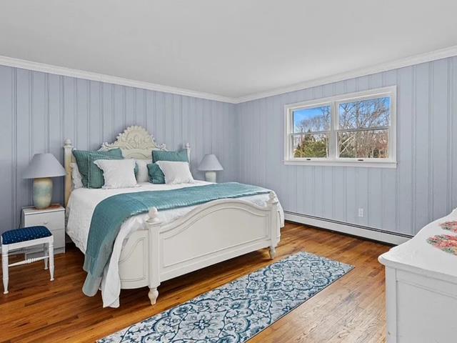 bedroom featuring a baseboard radiator, crown molding, and wood finished floors