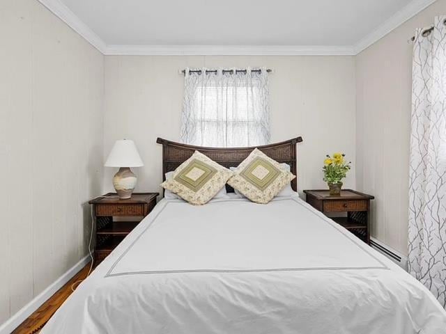 bedroom featuring crown molding, baseboards, and wood finished floors